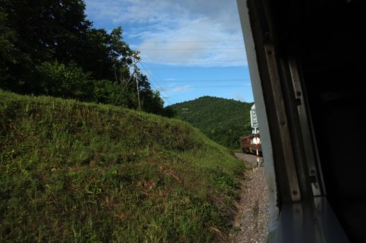 View from train window in motion of countryside and sky on sunny warm , in Thailand , 