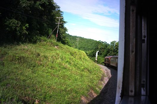 View from train window in motion of countryside and sky on sunny warm , in Thailand , Effect saturation