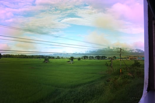 View from train window in motion of countryside and sky on sunny warm , in Thailand , Effect saturation