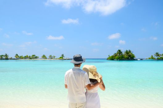 Young happy asian couple  in sunhat on white beach at summer vacation in Maldives island