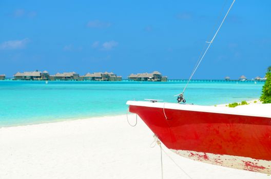 Boat on the white sand beach at maldives island