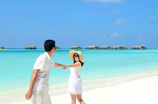 Young happy asian couple  in sunhat on white beach at summer vacation in Maldives island