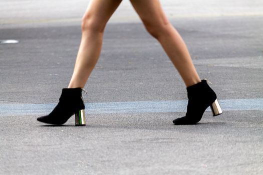 Legs of woman with high heels walking down the street