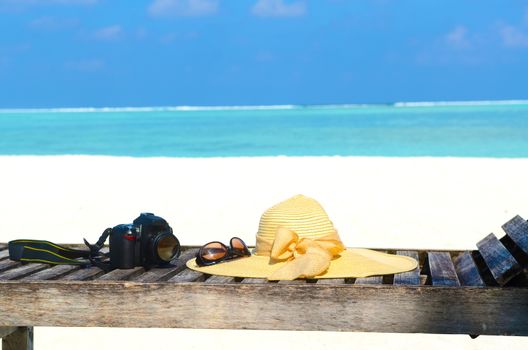 Deckchairs with sunhat, camera and sunglass on jetty in front of tropical resort at maldives island