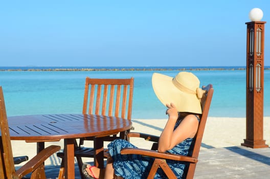 close-up portrait of a beautiful  asian girl in sunhat with long hair on a background of blue sea and sky with clouds on a sunny day, lifestyle, posing and smiling.