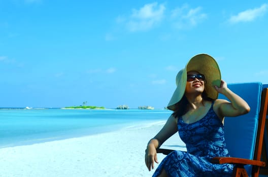 close-up portrait of a beautiful young asian girl with long hair on a background of blue sea and sky with clouds on a sunny day, lifestyle, posing and smiling.