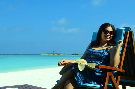 close-up portrait of a beautiful young asian girl with long hair on a background of blue sea and sky with clouds on a sunny day, lifestyle, posing and smiling.