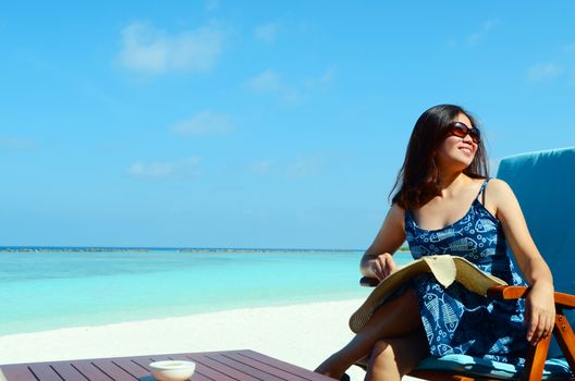 close-up portrait of a beautiful asian girl with long hair on a background of blue sea and sky with clouds on a sunny day, lifestyle, posing and smiling.