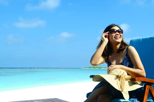 close-up portrait of a beautiful young asian girl with long hair on a background of blue sea and sky with clouds on a sunny day, lifestyle, posing and smiling.