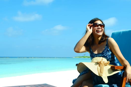 close-up portrait of a beautiful young asian girl with long hair on a background of blue sea and sky with clouds on a sunny day, lifestyle, posing and smiling.