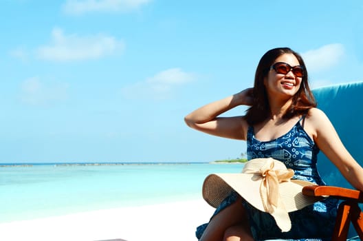 close-up portrait of a beautiful young asian girl with long hair on a background of blue sea and sky with clouds on a sunny day, lifestyle, posing and smiling.