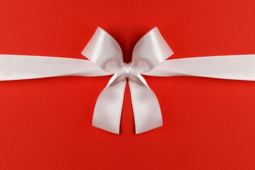 White gift bow on red background copy space for text