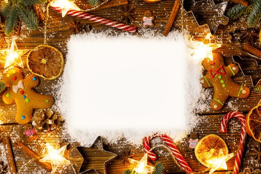 Christmas food frame. Gingerbread cookies, spices and decorations on wooden background with copy space on snow