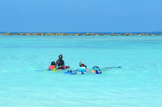 Group of friends ready to snorkeling under the guidance of coach in the clear sea at maldives island .