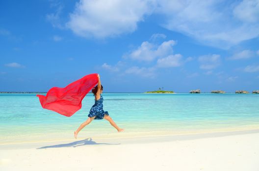 Pretty young asian girl is jumping up in the air at the beach