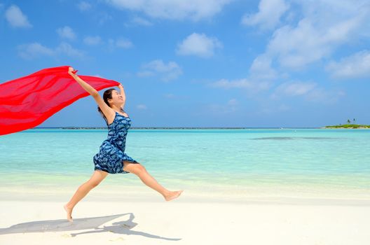 Pretty young asian girl is jumping up in the air at the beach