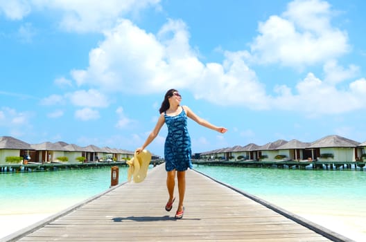 close-up portrait of a beautiful asian girl with long hair on a background of blue sea and sky with clouds on a sunny day, lifestyle, posing and smiling.