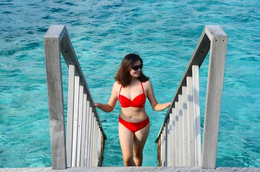 Portrait of happy young woman at beautiful water villa at Maldives island. Travel and Vacation. 
