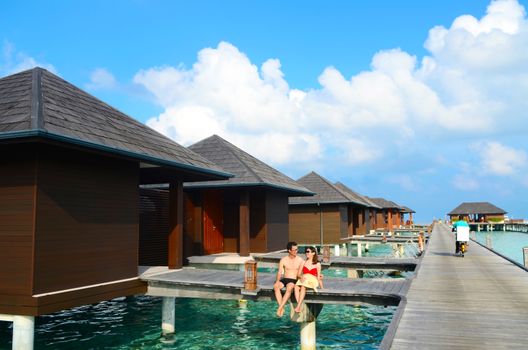 Asian couple on a tropical beach jetty at villa water resort,Maldives