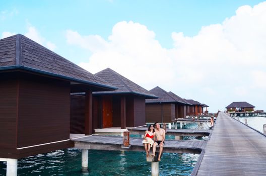 Asian couple on a tropical beach jetty at villa water resort,Maldives