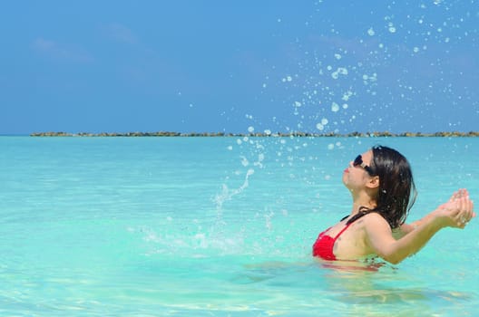 Woman swim and relax in the crystal-blue sea of tropical beach at  Maldives islands. Happy lifestyle concept. 