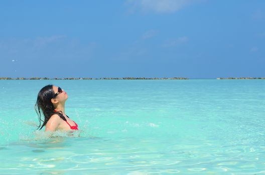 Woman swim and relax in the crystal-blue sea of tropical beach at  Maldives islands. Happy lifestyle concept. 