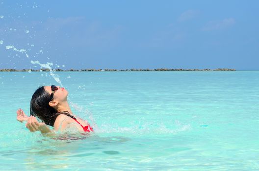 Woman swim and relax in the crystal-blue sea of tropical beach at  Maldives islands. Happy lifestyle concept. 