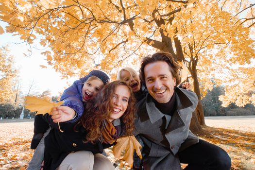 Happy smiling family of parents and children having fun hugging in autumn park