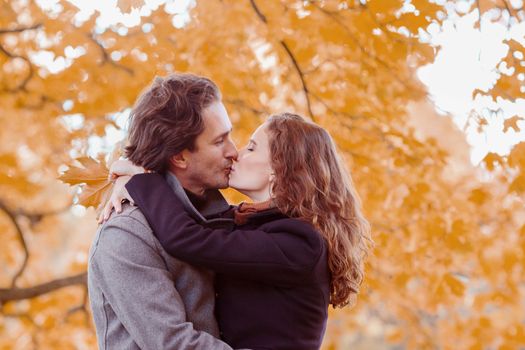 love, relationship, family and people concept - couple with maple leaves kissing in autumn park