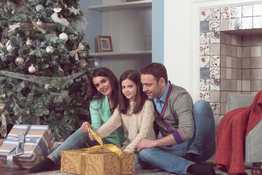 Happy family gather near Christmas tree with presents