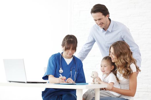 Young pediatrician doctor talking with girl and her parents