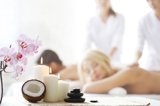 Spa massage tools and women getting massage on background