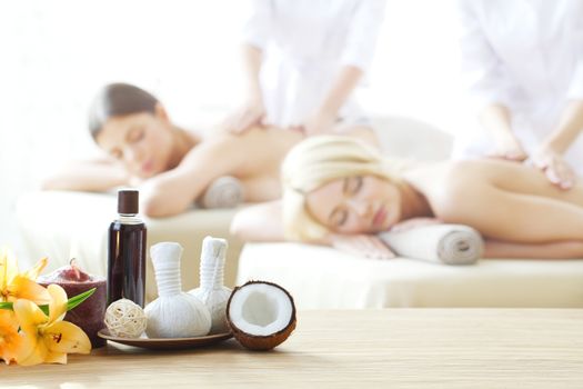 Spa massage tools and women getting massage on background