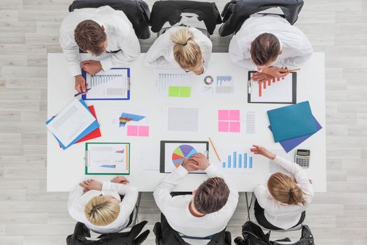 Business people work with statistics documents with tables and diagrams sitting around the table