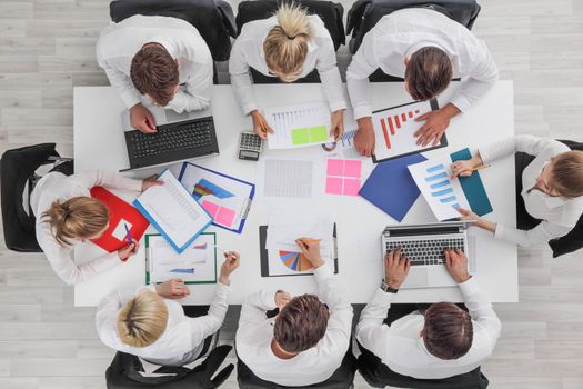 Business people work with statistics documents with tables and diagrams sitting around the table