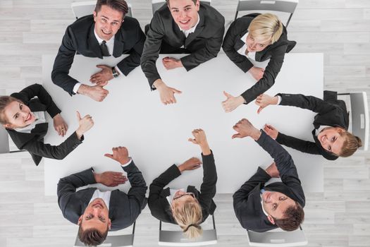 Diverse business people sitting around the table on a meeting and smiling showing thumbs up