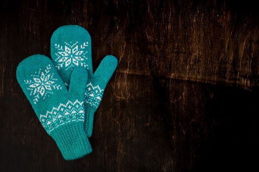 a pair of blue knitted mittens on a dark blue-green-brown wooden vintage background, copy space.