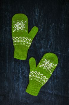 a pair of blue-green knitted mittens on a dark blue-green-brown wooden vintage background, copy space.