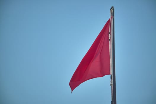 Pole with raised red flag, symbol of danger for bathers and navigators.