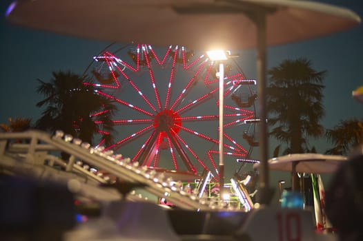 View of a panoramic wheel with the sunset behind, taken in a luna park in a seaside resort.