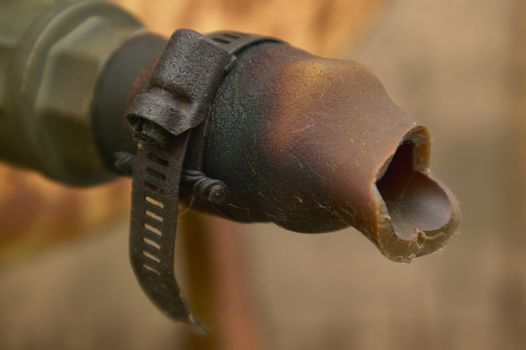 Detail of an old rusty iron clamp holding an old piece of time ruined pipe tied.