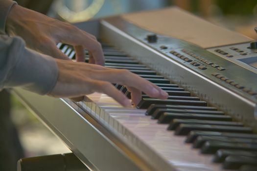 Hand of a musician pressing the keys of an electronic keyboard while playing at a concert