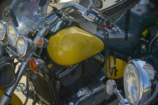 detail of the tank and engine of a yellow custom bike, motorcycle inserted in a rally with other bikes, of which sprouts some details.