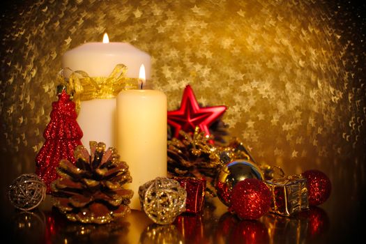 Christmas decoration of burning candle and decor over golden star bokeh background