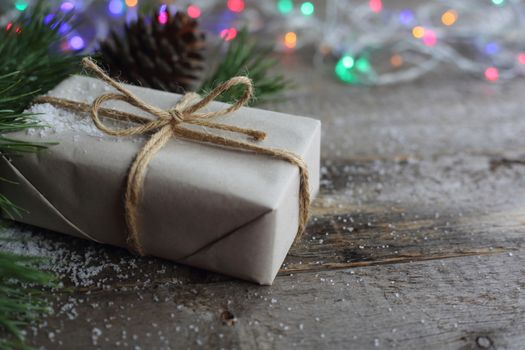 Simple Christmas gift on wooden background with snow and garland