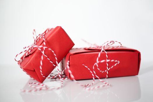 Christmas gift boxes wrapped in red paper and bow of dtriped rope on white background