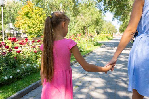 A girl walks along the alley and holds mom's hand