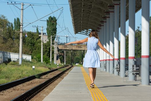 Young beautiful girl goes on the platform holding her arms outstretched to the side