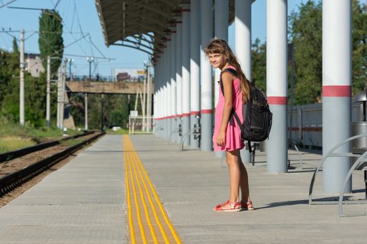 The eight-year-old girl on the platform of the railway station turned around and looked into the frame