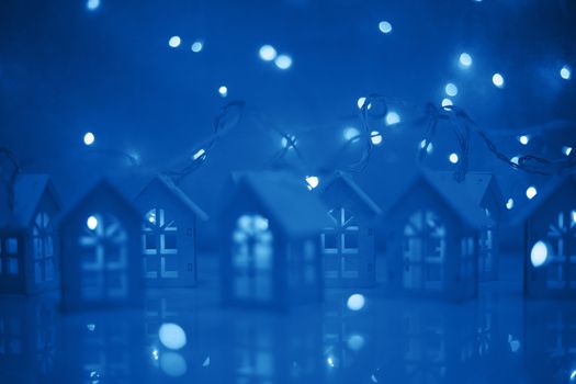 Christmas card of small glowing toy houses garland over bokeh lights background with copy space for text